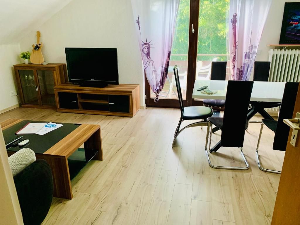 A living room with a television, a dining table, and chairs.