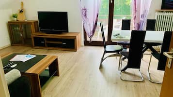 A living room with a television, a dining table, and chairs.