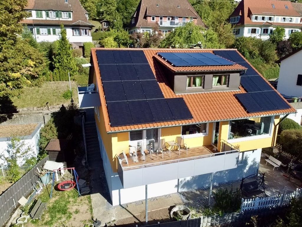 A two-story house with a balcony and solar panels on the roof.