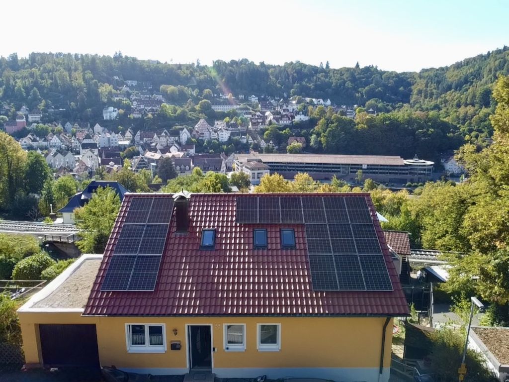 Ein Wohngebäude mit rotem Ziegeldach und Solaranlage.