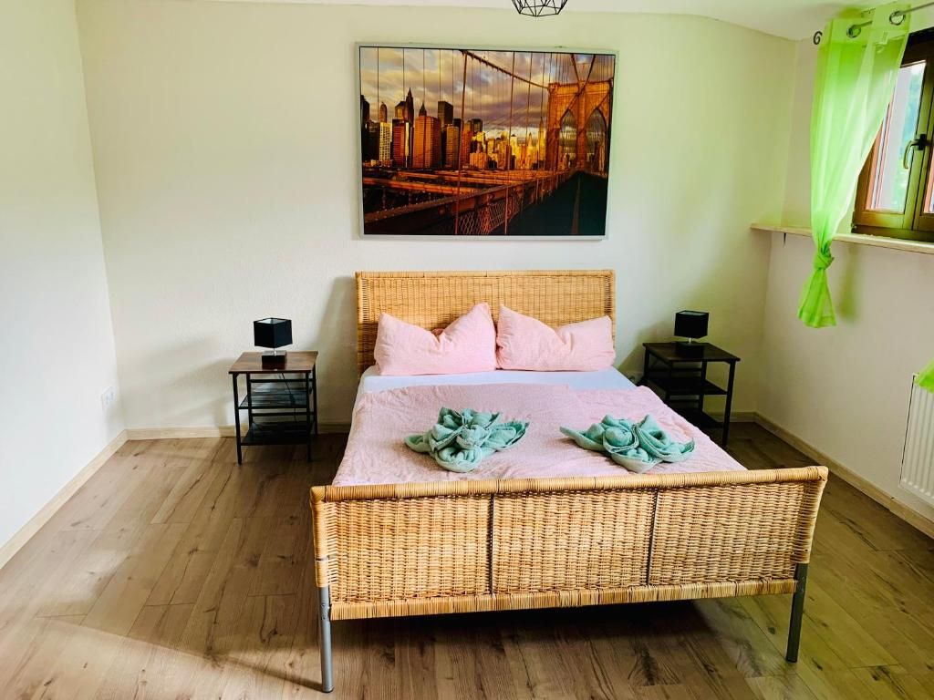 Ein Schlafzimmer mit einem Bett, einem Gemälde, einem Fenster mit Vorhängen und einem Nachttisch.