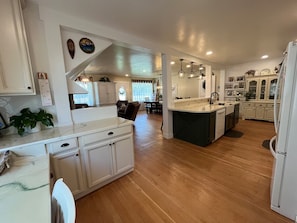 A spacious kitchen with a large island, wooden flooring, and white cabinetry. - 12 BDR ID Retreat, Hot Tub, beds for 37+, Events (Nampa)
