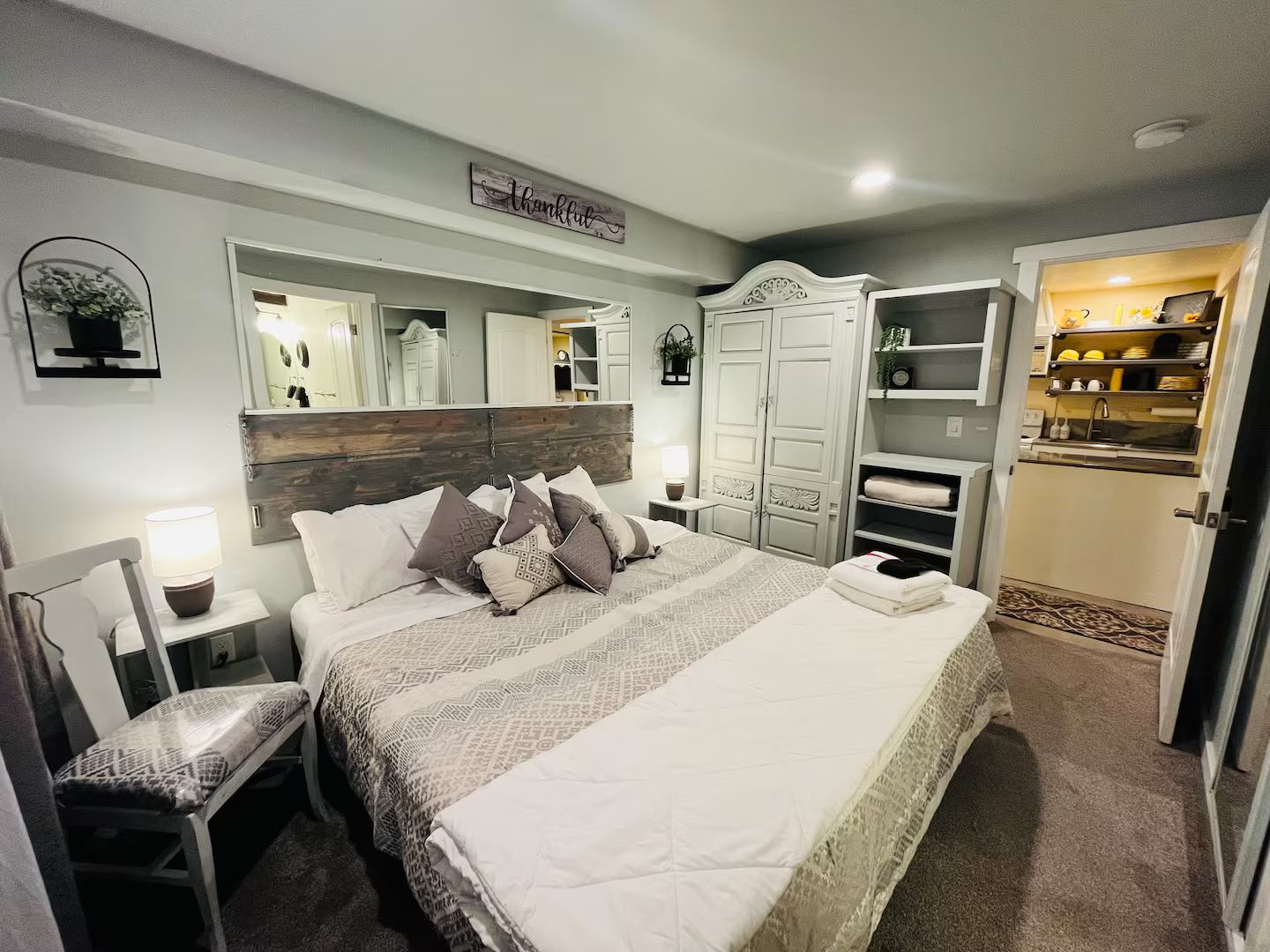 Ein Schlafzimmer mit einem großen Bett, einem Nachttisch mit Lampe, einem Kleiderschrank und einem Spiegel.