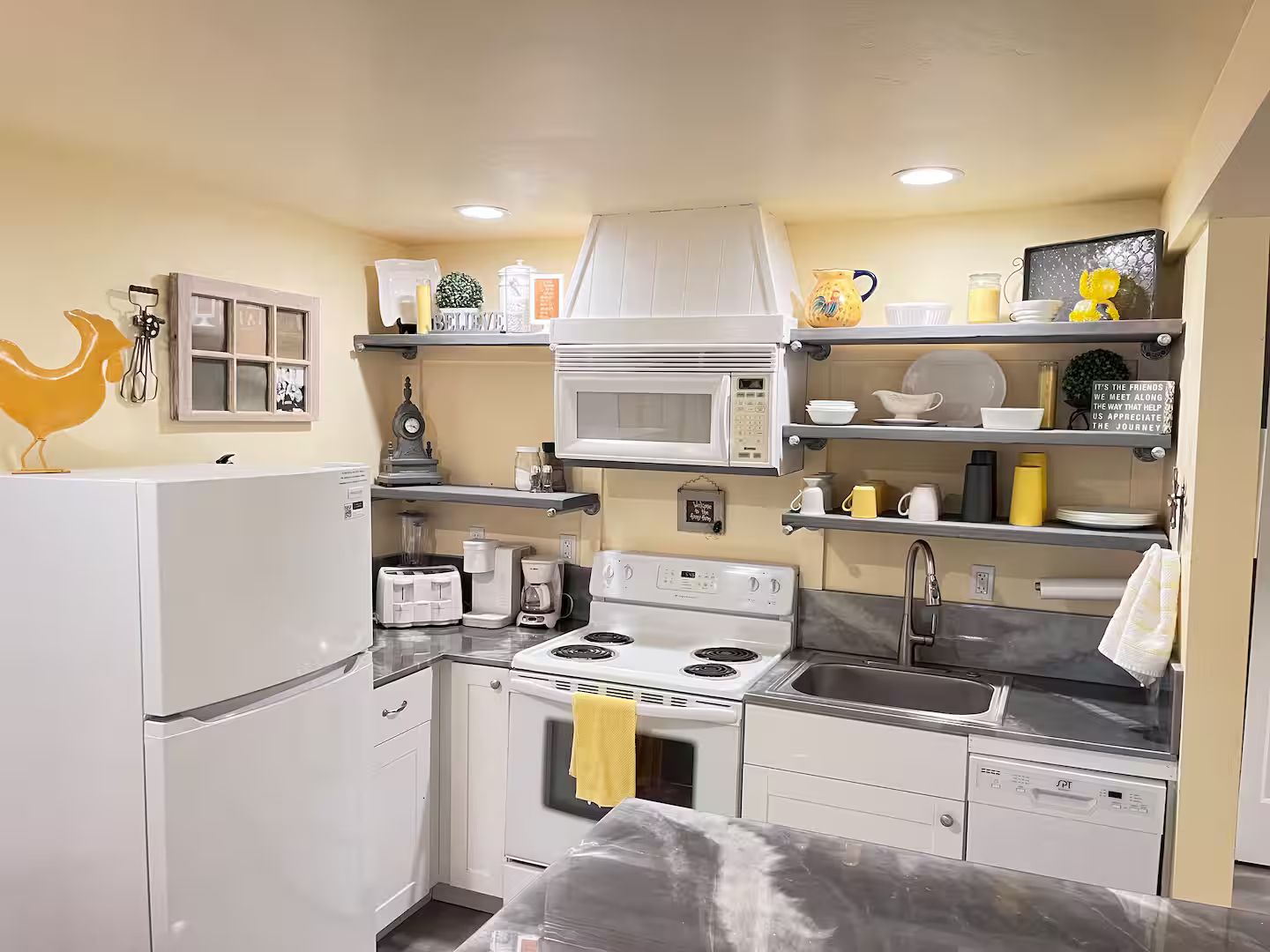 Une cuisine compacte équipée d’un four à micro-ondes, d’une cuisinière, d’un évier et de divers appareils électroménagers.
