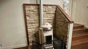 Ein Kamin aus Stein mit einer Glasschiebetür, eine Wanduhr und eine Treppe im Hintergrund.