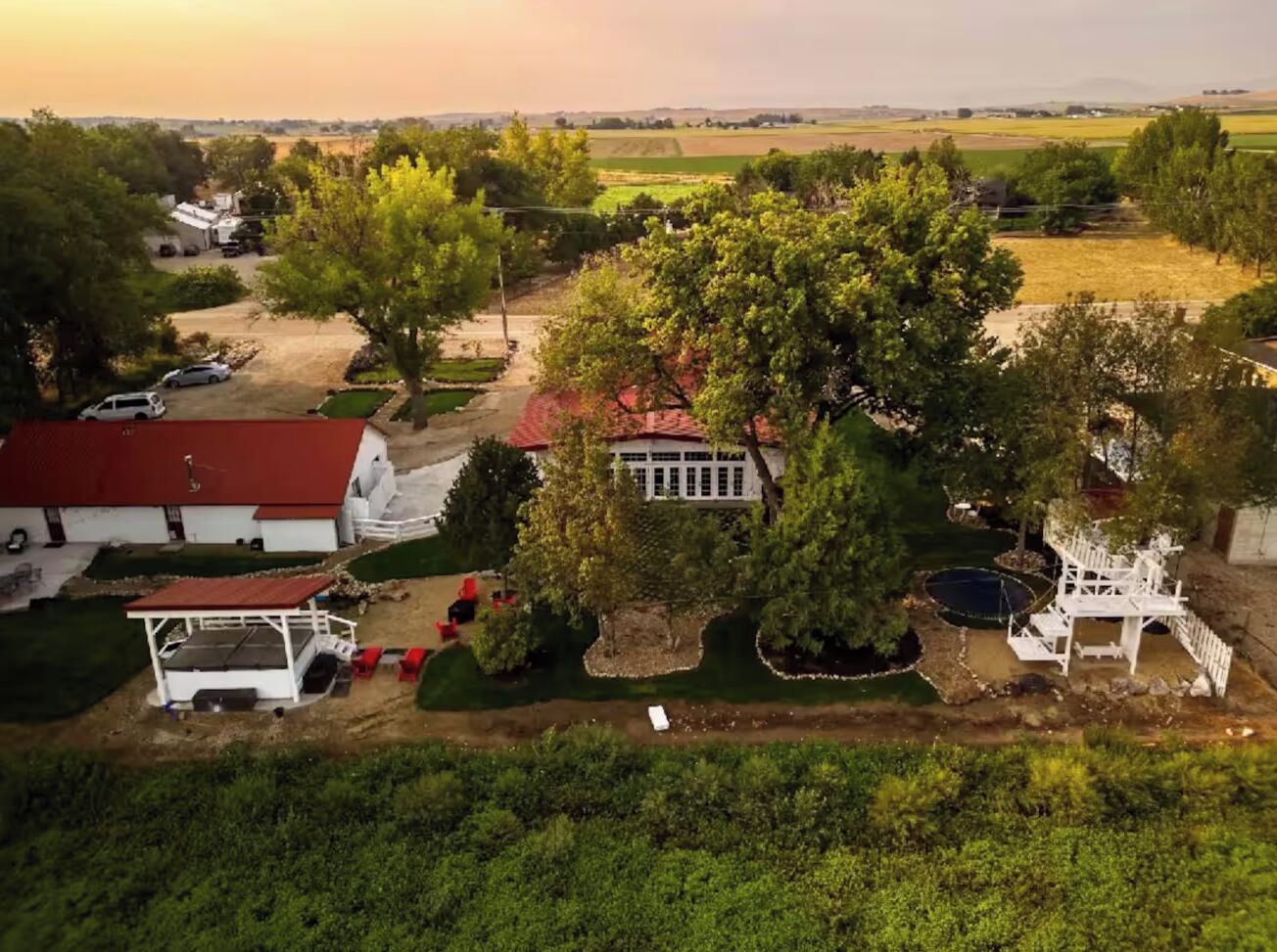 Uma propriedade rural com um celeiro, uma casa branca e uma piscina.