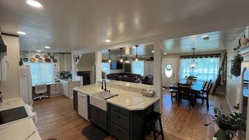 A modern kitchen with a central island, built-in appliances, and a dining area with a table and chairs.