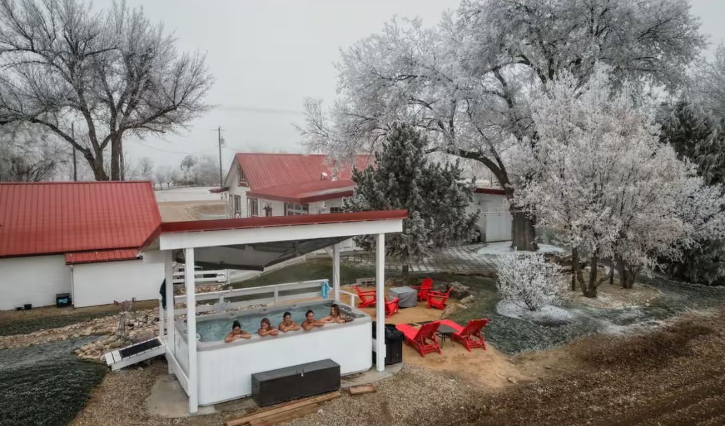 A hot tub area with a covered seating area and red chairs.