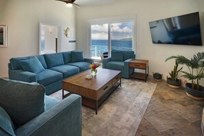 Ein modernes Wohnzimmer mit einer Couch, Sesseln, einem Couchtisch und einem Fernseher.