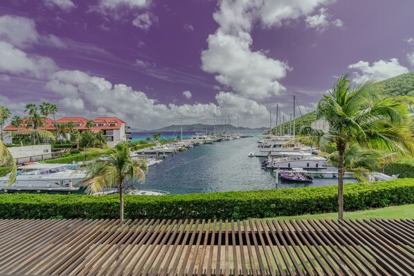 A marina with boats docked, a wooden deck in the foreground, and a building with a red roof in the background. - 1Br condo in Sapphire Beach Resort - pool & beach! Sleeps 4 (St. Thomas)