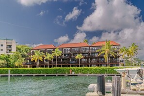 A multi-story hotel with a red roof, located near a body of water with palm trees and a dock. - 1Br condo in Sapphire Beach Resort - pool & beach! Sleeps 4 (St. Thomas)
