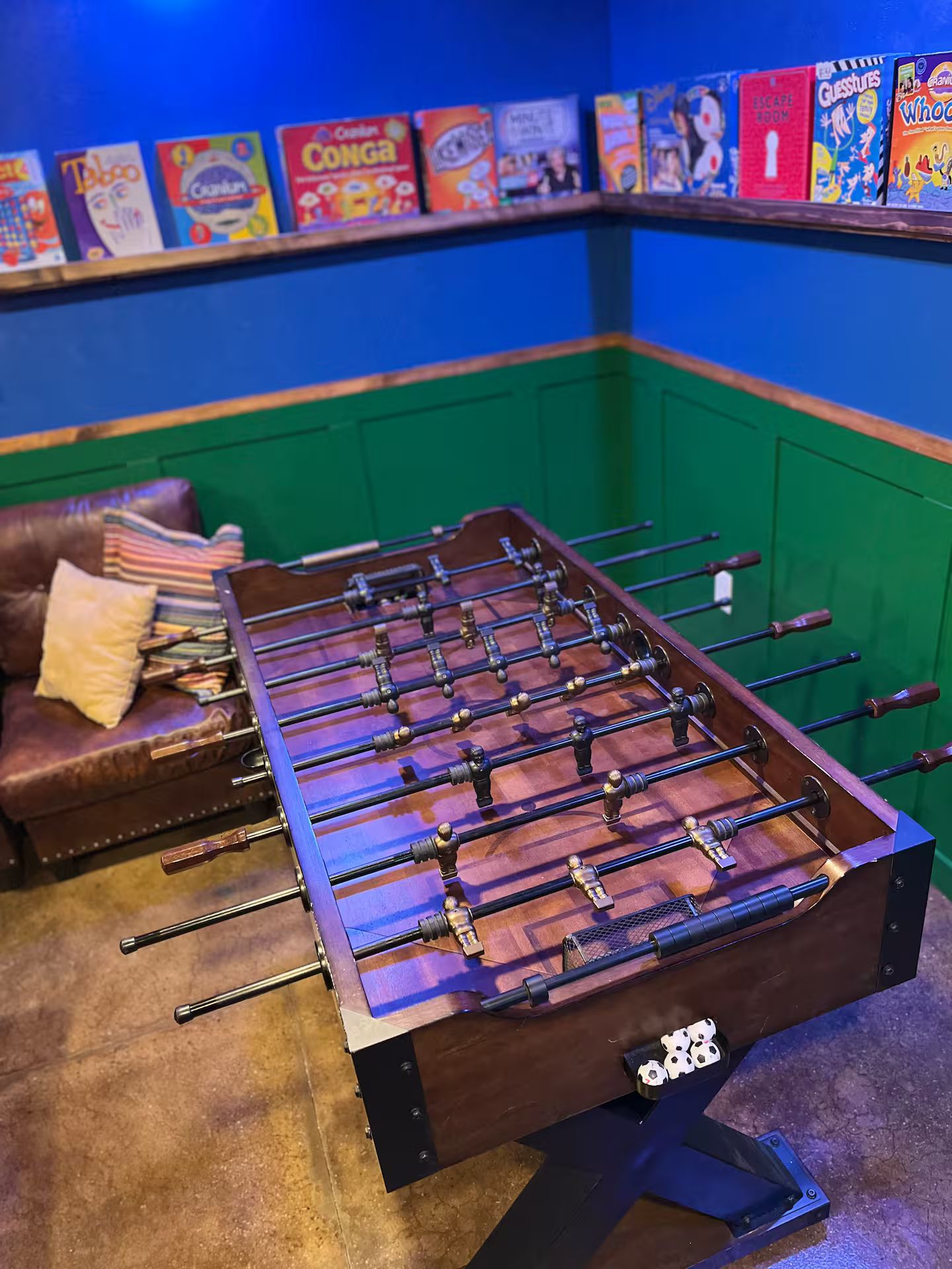 Ein Kicker steht in einem Raum mit grüner Wand und blauer Decke.