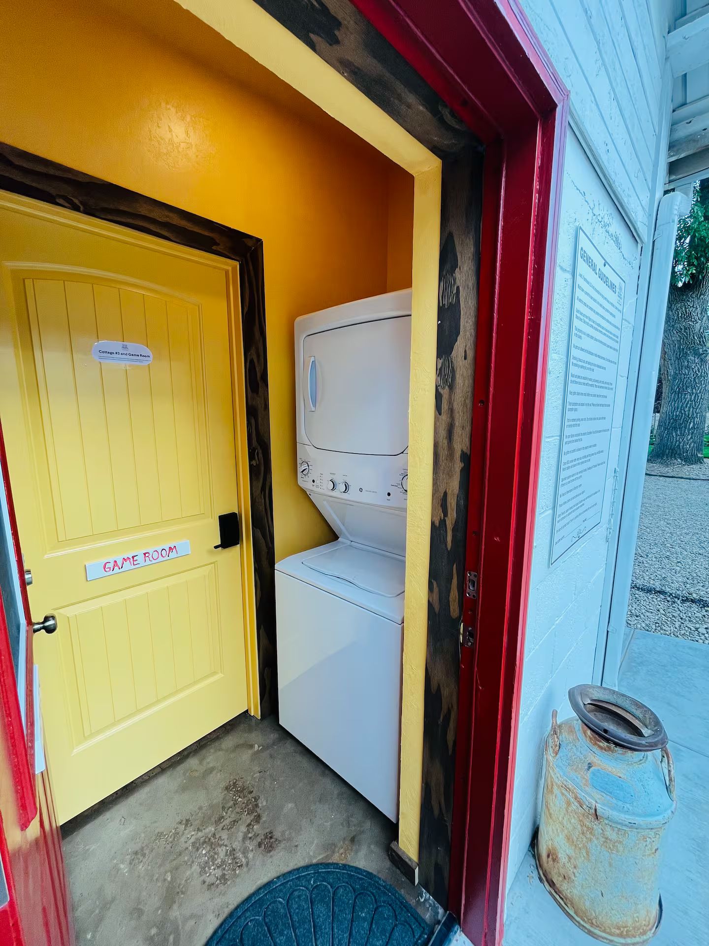 A laundry room with a yellow door labeled 'Cottages #3 and Game Room,' a white washing machine, and a red and white wall with a 'General Guidelines' sign.