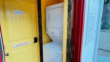 A laundry room with a yellow door labeled 'Cottages #3 and Game Room,' a white washing machine, and a red and white wall with a 'General Guidelines' sign.
