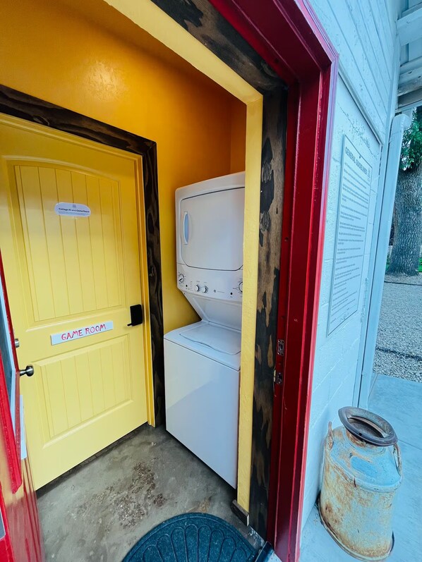 A laundry room with a yellow door labeled 'Cottages #3 and Game Room,' a white washing machine, and a red and white wall with a 'General Guidelines' sign.