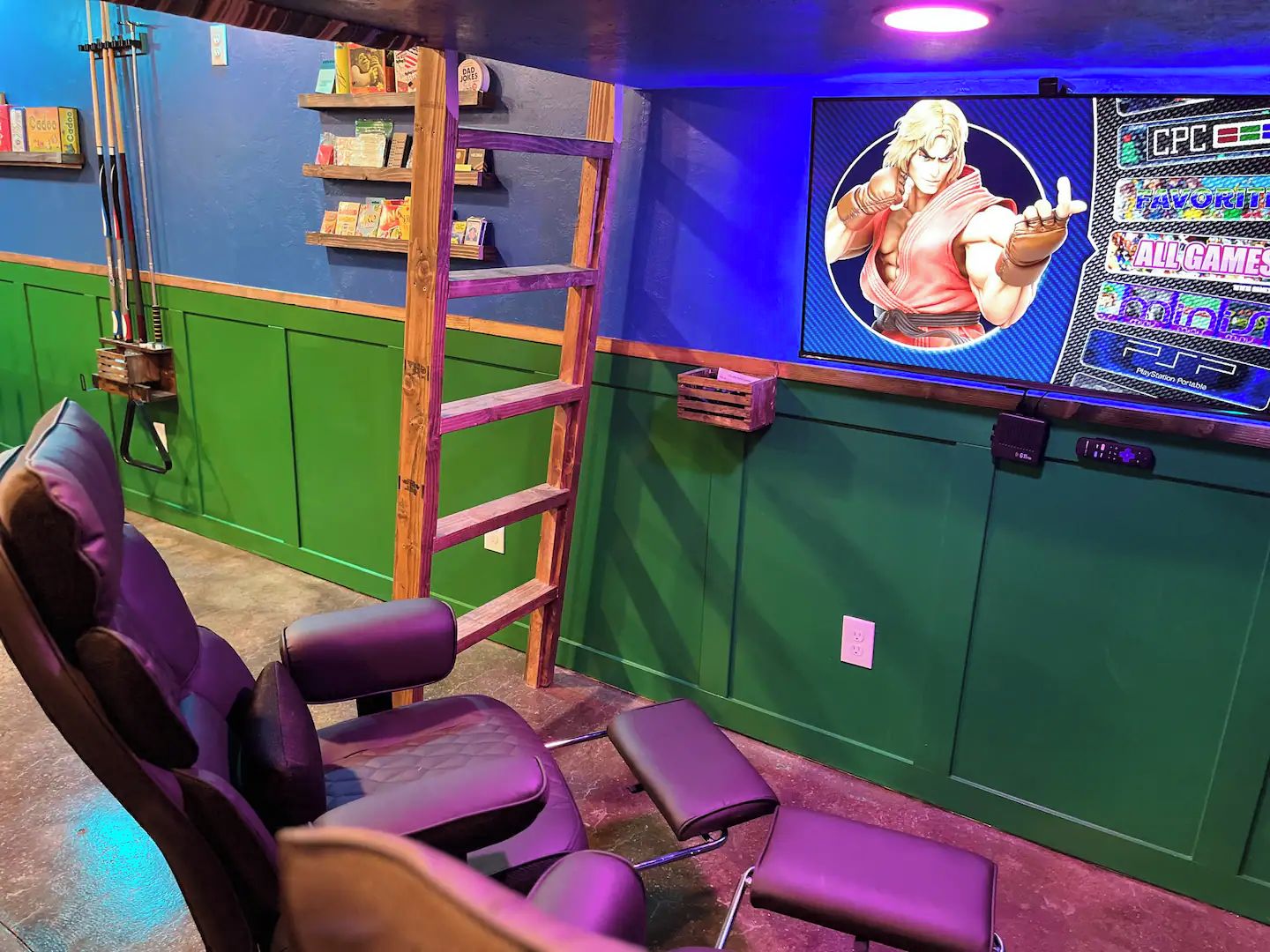 Espaço de jogos com escada de madeira, cadeira gamer roxa e tela fixada na parede exibindo um jogo de vídeo.