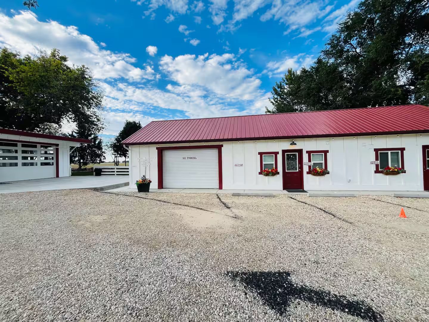 A building with a red roof and white walls, a garage door, and flower boxes on the windows.