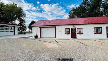 A building with a red roof and white walls, a garage door, and flower boxes on the windows.
