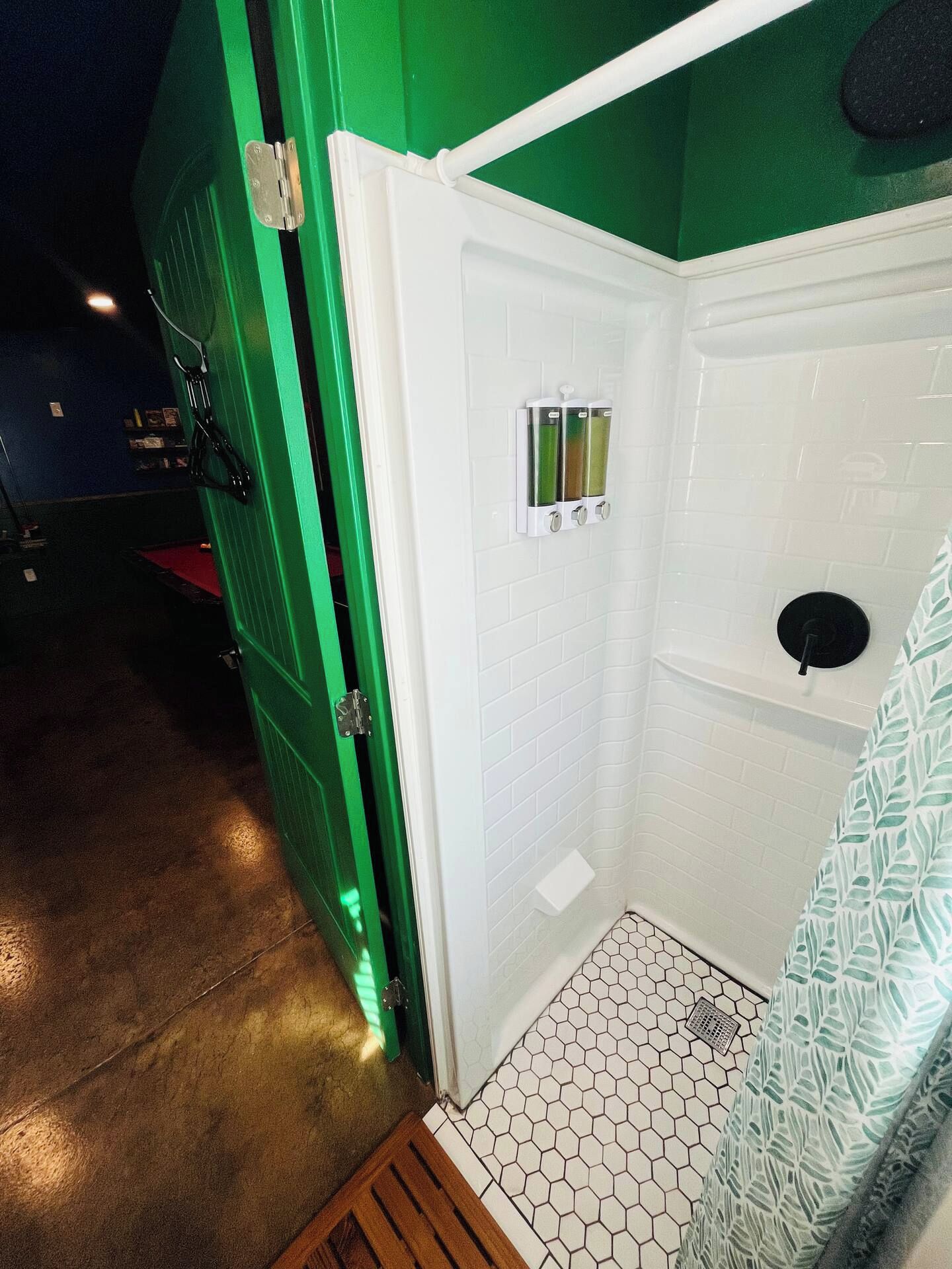 A small, enclosed shower area with a white tiled wall and a hexagonal patterned floor.