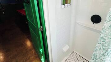 A small, enclosed shower area with a white tiled wall and a hexagonal patterned floor.