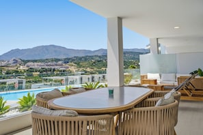 A modern outdoor seating area with a view of a mountain and a pool. - Marina Retreat by IIM (Estepona)