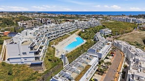A modern residential complex with a central swimming pool, multiple balconies, and a view of the sea. - Marina Retreat by IIM (Estepona)