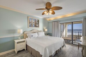 A bedroom with a bed, nightstands, a ceiling fan, a painting, and a balcony with a view. - Shipwatch D302 (Pensacola)