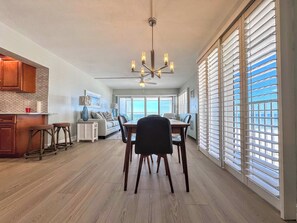 A spacious kitchen with a dining area, large windows with blinds, and a ceiling fan. - Island House Beach Club 5D - Beautiful Beachfront Condo (Fort Myers Beach)