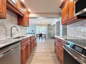 A kitchen with wooden cabinets, a stainless steel sink, and a built-in oven. - Island House Beach Club 5D - Beautiful Beachfront Condo (Fort Myers Beach)
