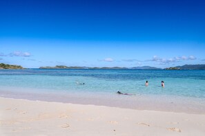A beach with clear blue water, sandy shore, and distant mountains. - 1BR condo on Sapphire Beach - sleeps 4! (St. Thomas)