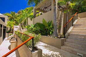 A modern outdoor area with a staircase, palm trees, and a building facade. - The BEST Wedding Spot! 2 pools, gym, beachfront & MUCH MORE! (St. Thomas)