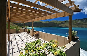 A wooden pergola with a tiled floor overlooking a turquoise sea and green hills. - The BEST Wedding Spot! 2 pools, gym, beachfront & MUCH MORE! (St. Thomas)