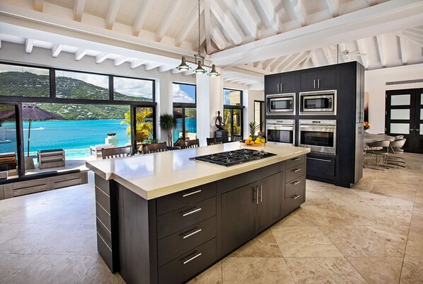 A modern kitchen with a large island, built-in appliances, and a view of the sea. - The BEST Wedding Spot! 2 pools, gym, beachfront & MUCH MORE! (St. Thomas)