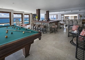 Ein Poolbereich mit Billardtisch, Bar und Sitzgelegenheit mit Meerblick.