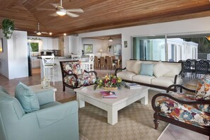A spacious living area with a sofa, a coffee table, and a patterned armchair. A dining area with chairs and a table is visible in the background. - Amazing harbor views & central, gated location!! 5 en-suite baths! (St. Thomas)