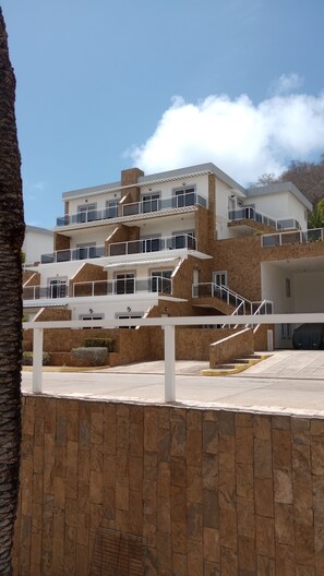 A multi-story building with balconies, a stone facade, and a clear sky. - Porlamar Lomas del Encanto | Relaxation, Comfort & Terrace with a View of the Pool (Porlamar)
