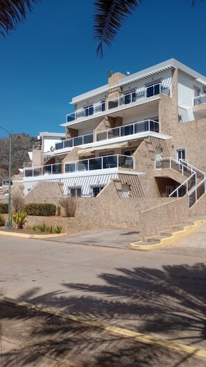 A multi-story building with balconies, a staircase, and a paved area in front. - Porlamar Lomas del Encanto | Relaxation, Comfort & Terrace with a View of the Pool (Porlamar)