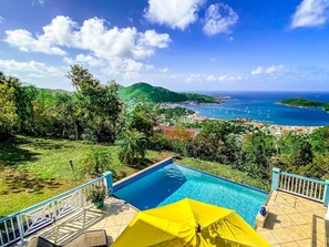 A swimming pool with a yellow umbrella, surrounded by a deck with railings, overlooking a coastal town and the sea. - Incredible 3 BR Villa with Fabulous 160º Views of Charlotte Amalie Harbor! (St. Thomas)