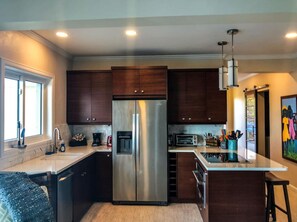 A modern kitchen with dark wood cabinets, a stainless steel refrigerator, a built-in oven, and a window providing natural light. - Cliff-side 5BR villa - stunning down-island views & 5 mins from Magen`s Bay! (St. Thomas)