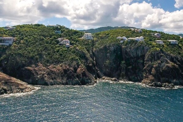 A coastal landscape with buildings perched on a cliff overlooking the sea. - Cliff-side 5BR villa - stunning down-island views & 5 mins from Magen`s Bay! (St. Thomas)