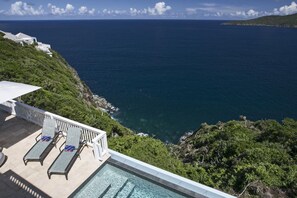Ein Poolbereich mit Liegestühlen und Meerblick.