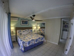 A bedroom with a bed, a ceiling fan, a nightstand, a dresser, and a door leading to another room. - 2br on Cowpet Beach w/Huge pool & 2 restaurants! (St. Thomas)