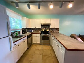 A kitchen with white cabinets, a microwave, an oven, and a sink. - 2BR just steps away from the beach and pool (St. Thomas)