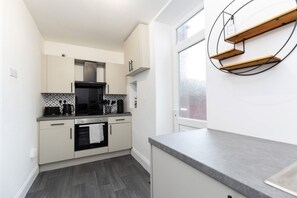 A modern kitchen with white cabinets, a built-in oven, and a grey countertop. - The Cosy Pavilion: Stylish 2BR Home with Free Street Parking (Burnhope)