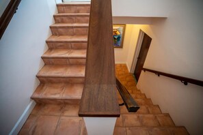 Eine Holzhandläufe und ein Geländer an einer Treppe mit Terrakottafliesen.
