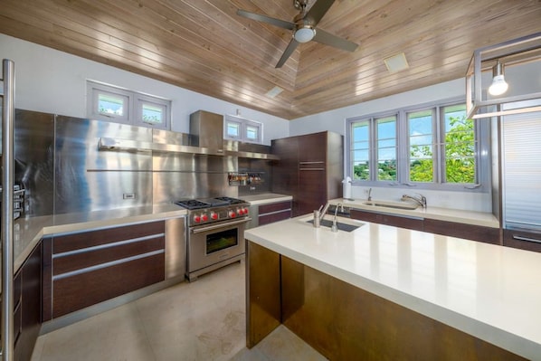 A modern kitchen with stainless steel appliances, wooden ceiling, and large windows. - Vessup View · 5BR -Walk to the beach! Close to the Ritz Carlton! (St. Thomas)
