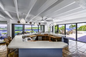 Een moderne keuken met een groot eiland, grote ramen en uitzicht op de oceaan.