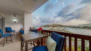 A balcony with a table and chairs, overlooking a marina with boats and buildings in the background. - GORGEOUS 2BR Condo on the beach! Newly remodeled, sleeps 6. (St. Thomas)