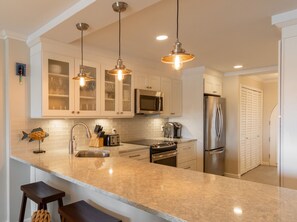 A modern kitchen with a large island, stainless steel appliances, and pendant lighting. - GORGEOUS 2BR Condo on the beach! Newly remodeled, sleeps 6. (St. Thomas)