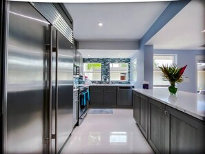 Une cuisine moderne dotée d’appareils électroménagers en acier inoxydable, de meubles de couleur sombre et d’un revêtement mural en carreaux.